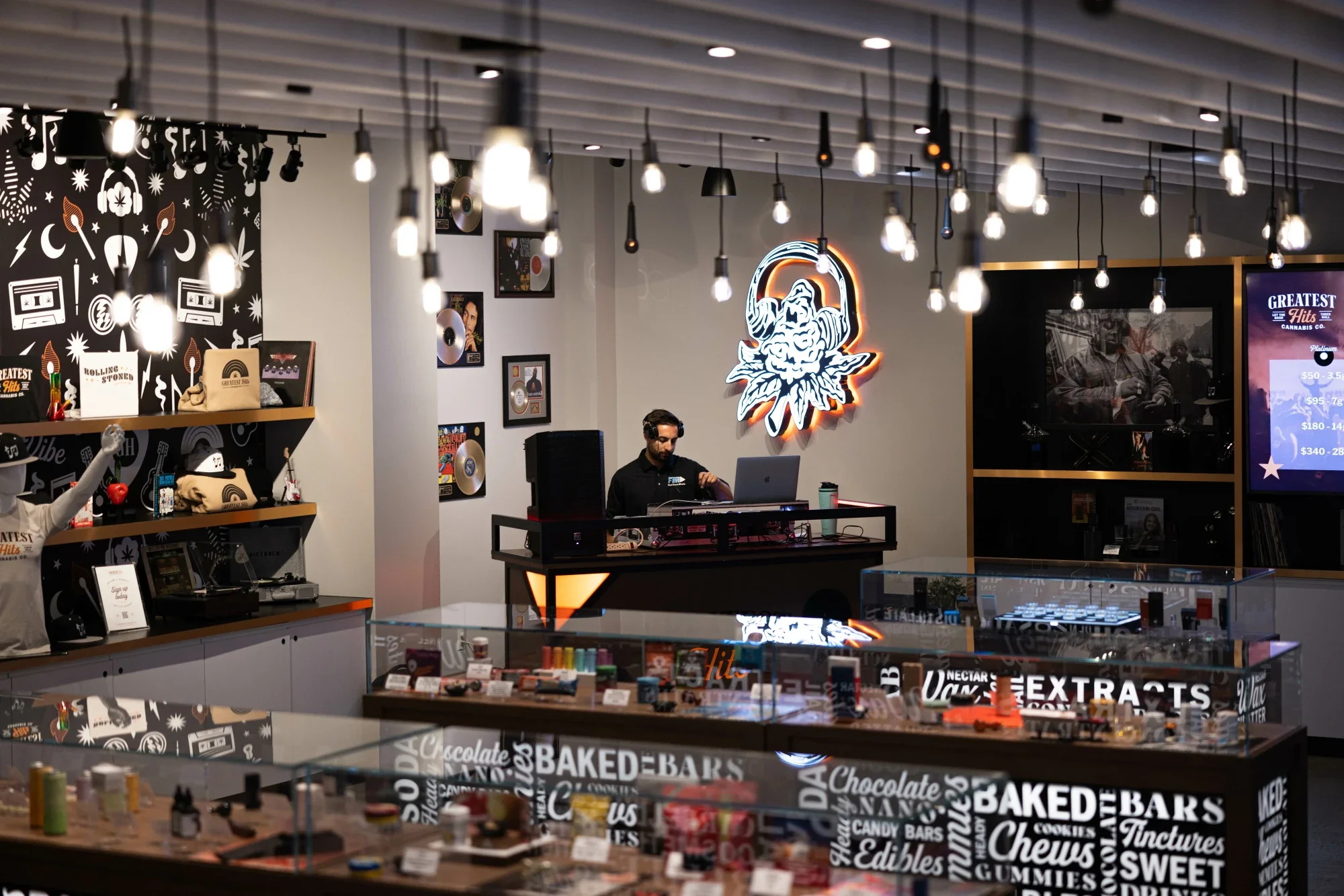 The DJ booth under the neon mark, with gold records on the wall.