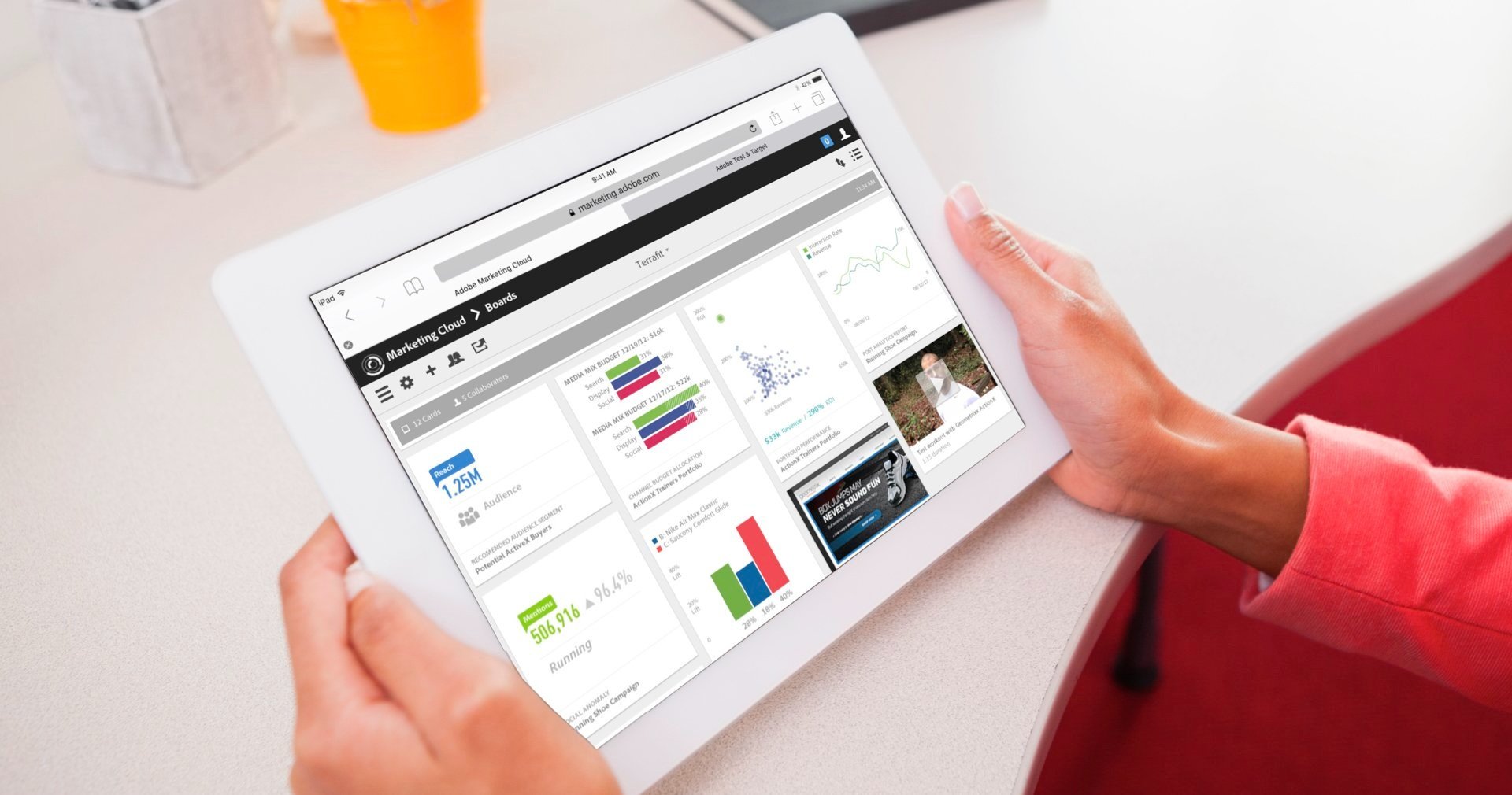 Hands holding a tablet with the Marketing Cloud feed, a red sleeve at the edge of the frame